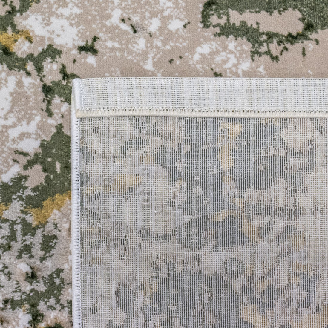 Paradise Living – Tapete Batik 38/005 Verde, detalhe do canto com verso antiderrapante texturado e costura de rebordo dupla, padrão verde e dourado visível