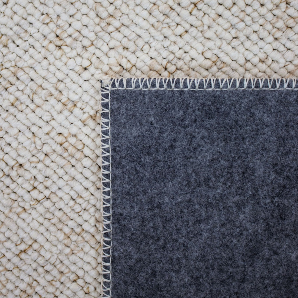 Paradise Living – Tapete Polo 71511/056 Bege Creme detalhe do canto dobrado mostrando frente em lã creme e verso em feltro cinzento escuro