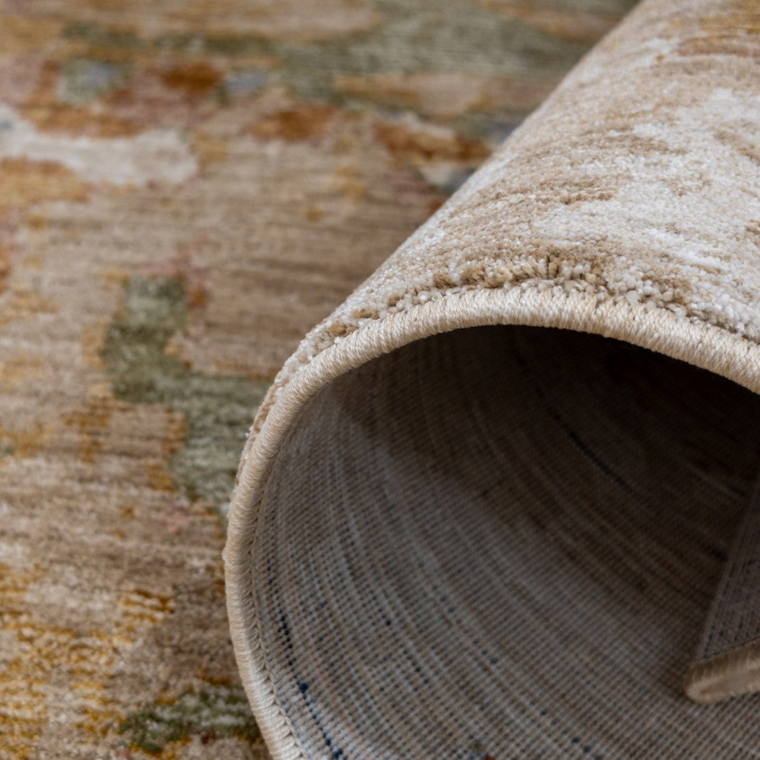 Paradise Living – Tapete Odense 7748/192 close-up do verso enrolado com orla em creme e textura multicolor em tons bege, verde e terracota