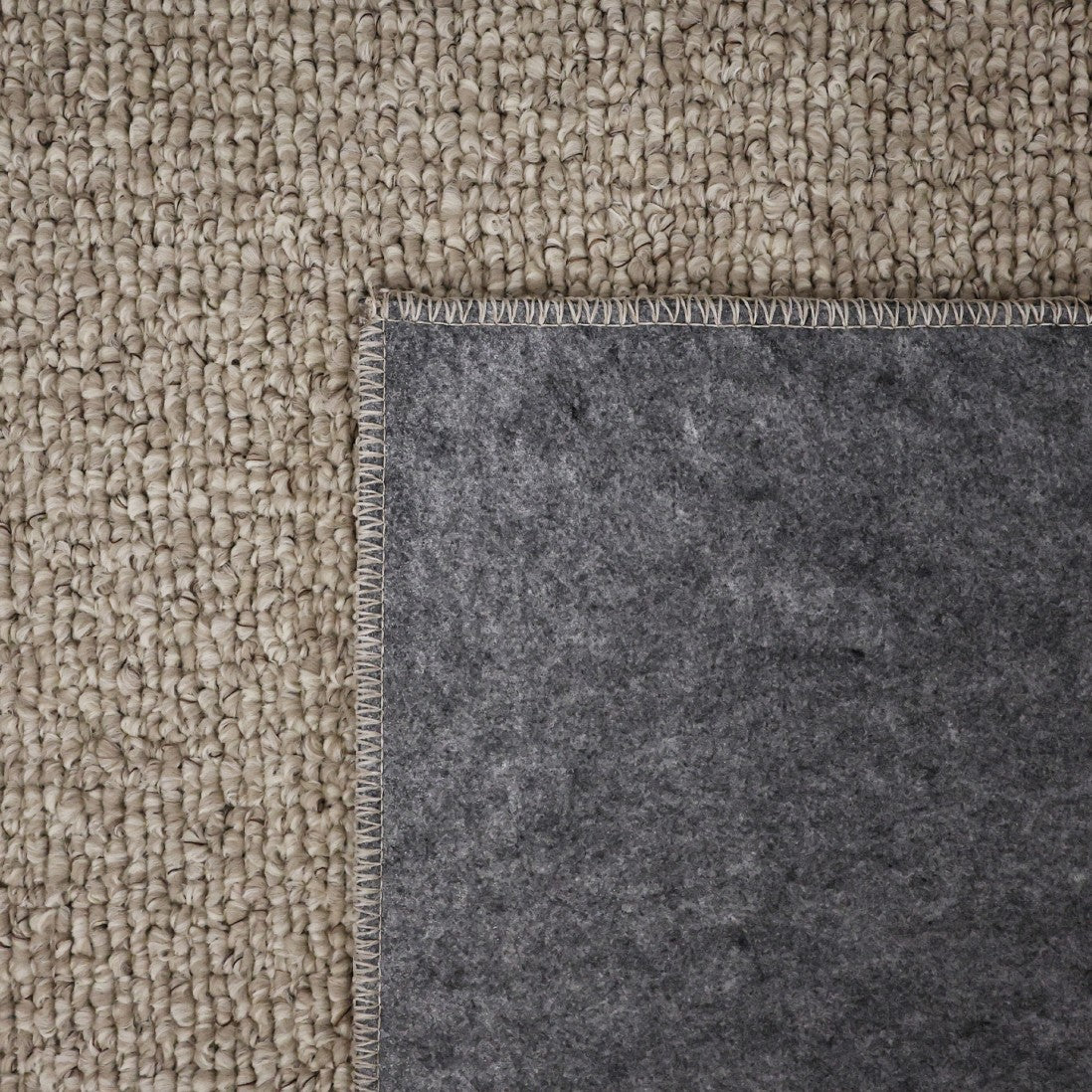 Paradise Living – Tapete Bhutan 71591/056 Bege detalhe do canto dobrado mostrando frente em bouclé bege e verso em feltro cinzento