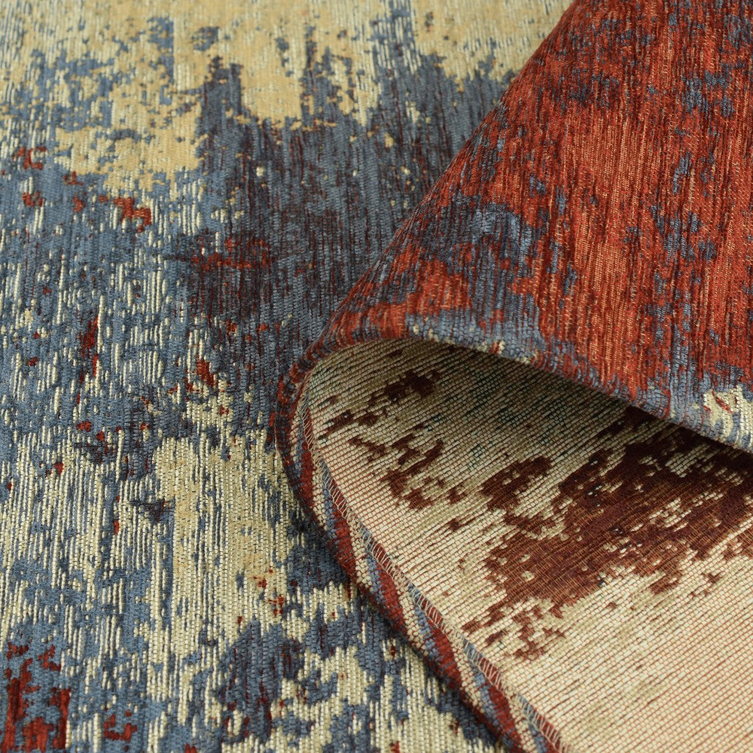 Paradise Living – Tapete Ametist Chenille 070 Multicolor close-up do canto enrolado mostrando textura chenille em tons vermelho, azul e bege e verso em tecido creme