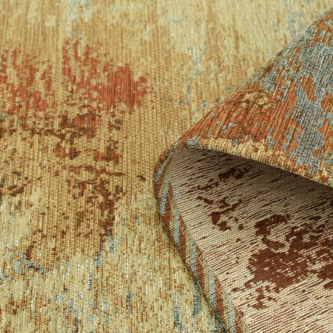 Paradise Living – Tapete Ametist Chenille 287 Multicolor close-up do canto enrolado mostrando textura chenille em tons bege, terracota e azul e verso em tecido creme