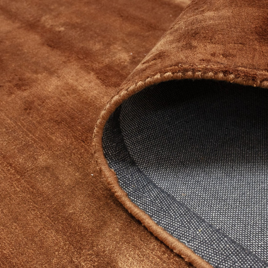 Paradise Living – Macro da superfície do Tapete Papua 192 Laranja Torrado em viscose, com textura sedosa e variações orgânicas de luz em tons terracota e cobre